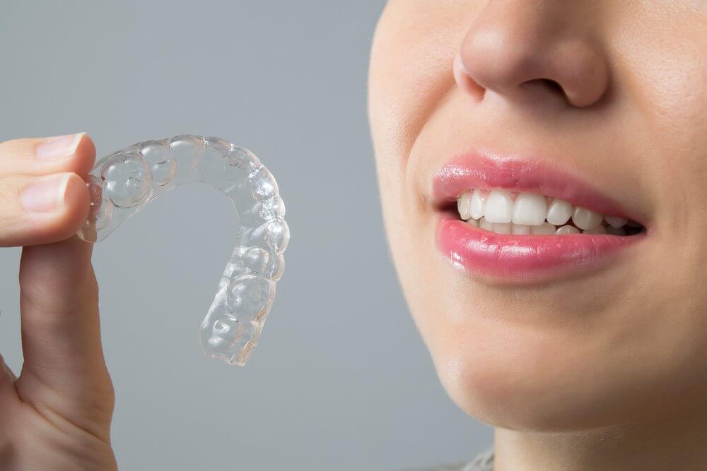 A patient holding up an Invisalign clear aligner tray