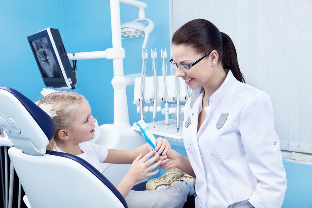 A dentist giving a young child a toothbrush and toothpaste