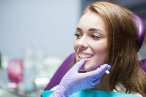 A female sitting in a purple dental chair while looking at the dentist