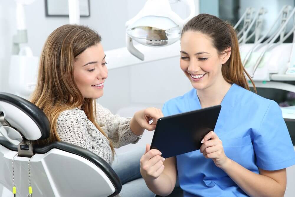 A dental assistant showing a patient her information on an iPad