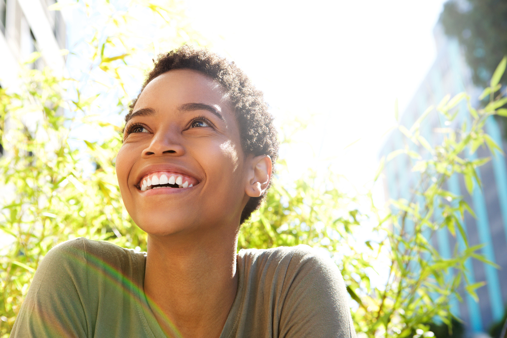 young woman with short hair smiles while looking upward while outside